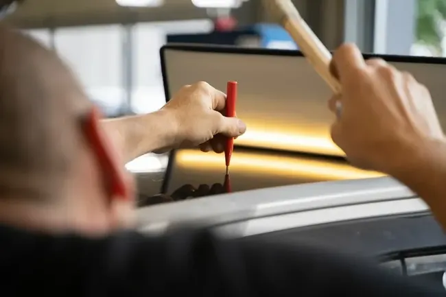 Precision work on a body panel under a PDR inspection light